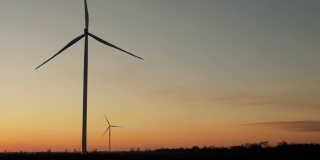 日落时田野上风力发电机和树木的剪影