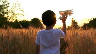 可爱的亚洲小孩在日落时分的稻田里玩玩具飞机。视频素材模板下载