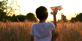 可爱的亚洲小孩在日落时分的稻田里玩玩具飞机。