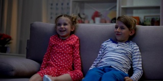 弟弟和妹妹笑着一起看搞笑的动画片，晚上一起娱乐