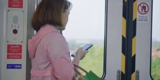 年轻女子在乘坐地铁时使用智能手机，慢镜头