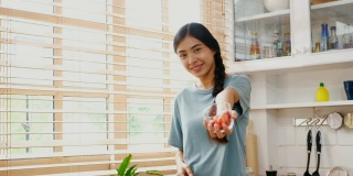 年轻的亚洲女人在家里的厨房里吃着幸福的草莓，人们健康的生活方式