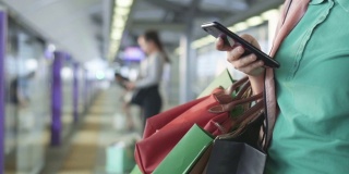 女人在火车站站台上使用智能手机的特写，慢镜头
