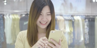亚洲女性使用信用卡和手机进行网上购物的场景在百货商店的服装店无现金，技术钱钱包和在线支付概念，信用卡模型