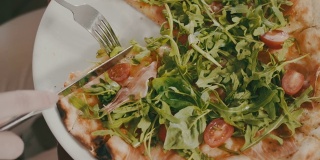 意大利餐厅。女人正在切披萨。叉子，刀，吃饭，午餐，意大利菜。