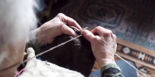 观点。一位老人织着精致而美观的毛衣，近处是一位老奶奶满是皱纹的双手正在织一件新的冬季毛衣，活跃的退休老人。