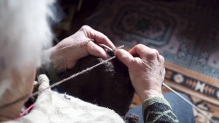 观点。一位老人织着精致而美观的毛衣，近处是一位老奶奶满是皱纹的双手正在织一件新的冬季毛衣，活跃的退休老人。视频素材模板下载