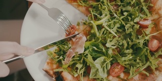 意大利餐厅。女人正在切披萨。叉子，刀，吃饭，午餐，意大利菜。