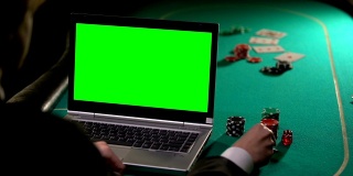男人用信用卡付扑克赌注，用笔记本电脑绿屏，在线赢钱