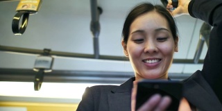 年轻的亚洲女性在公共交通上使用智能手机，在地铁上使用社交媒体女性上网