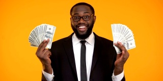 戴着眼镜的黑人男性展示着一堆现金，利润，利润丰厚的生意