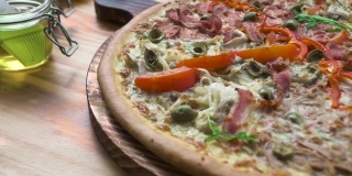 木桌上放着意大利比萨。原味热披萨配西红柿，培根和海鲜。传统意大利美食，美食理念。食品的背景