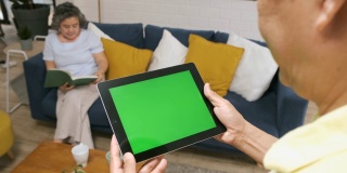 老人用绿屏平板电脑app来控制家里客厅里的空调和妻子。智能家居自动化控制概念。