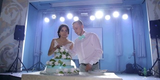 这对新婚夫妇切了一个漂亮的白色花结婚蛋糕。