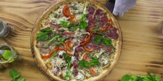 在披萨店的木桌上用滚轴刀切披萨。前视图。厨师厨师在意大利餐厅切热披萨。准备传统的意大利食物。国家食品的概念