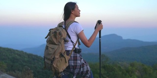 一位年轻的女游客正在山顶徒步旅行，观赏美丽的风景。