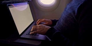 一名男子在飞机上敲打笔记本电脑——近距离观察