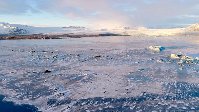 冰岛白色浮冰的鸟瞰图。我们可以看到背景中白色的大冰川，在夕阳下。