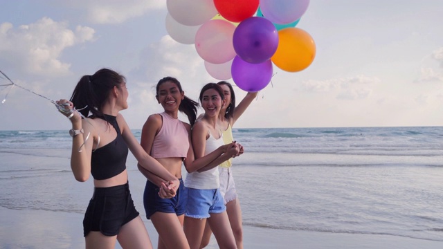 一群女朋友在海滩上玩着气球，背景是蓝天。在夏日阳光明媚的阳光下，朋友们在沙滩上嬉戏。假期——iStock