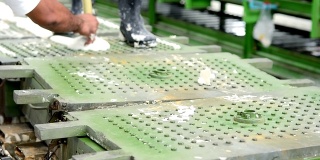 在橡胶枕厂的生产线上，工人将乳胶泡沫放入金属枕模的传送带上
