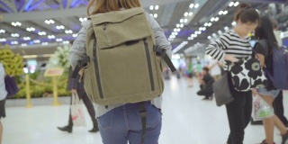 慢镜头-年轻的亚洲背包女走在国际机场。