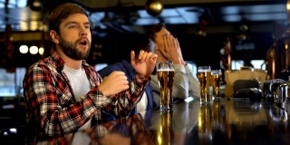 男性朋友喝啤酒，在酒吧为体育比赛欢呼，为输了而难过