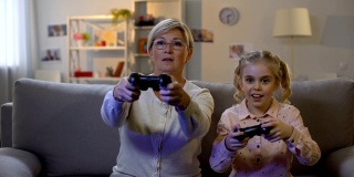 可爱的女孩和现代老奶奶在家里玩电子游戏，用操纵杆，休闲
