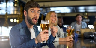 朋友们在酒吧里享受体育节目，喝酒为胜利，喝啤酒的传统