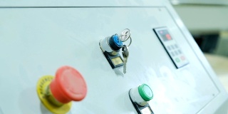 钥匙挂在一台现代数控木工机床的主控制面板上，特写。机器开始
