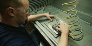 一名白种技术人员使用电动砂光机对生产设备中的铝制零件进行抛光和去毛刺