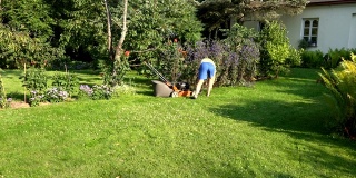 年轻人在自己家附近的绿色花园里和割草机一起工作。4K超高清视频剪辑。