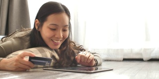 用信用卡在家里的平板电脑上网购的女人