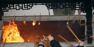 慢镜头火和香烟在中国传统寺庙，祈祷者把燃烧的香放入香炉，4K视频。