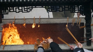 慢镜头火和香烟在中国传统寺庙，祈祷者把燃烧的香放入香炉，4K视频。视频素材模板下载