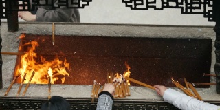 慢镜头火和香烟在中国传统寺庙，祈祷者把燃烧的香放入香炉，4K视频。