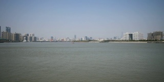 从徐汇滨江公园眺望上海外滩，蓝天背景下的摩天大楼，黄浦江上的货船，4K视频，慢镜头。