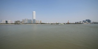 从徐汇滨江公园眺望上海外滩，蓝天背景下的摩天大楼，黄浦江上的货船，4K视频，慢镜头。