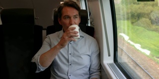 商务人士在火车上舒适地坐着，一边喝着咖啡，一边欣赏窗外的景色