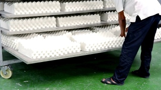 男人在工厂的架子上摆放白色乳胶枕头视频素材模板下载