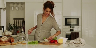 漂亮的孕妇在厨房做饭-正面视图
