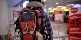 背包客拿着智能手机走向机场值机柜台