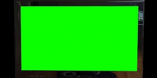 现代平板电视在黑色背景下的绿色屏幕慢慢缩小。用你自己的文本或素材代替绿色屏幕。