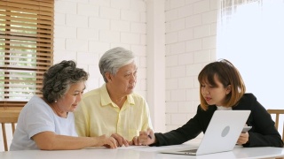 亚洲资深夫妇在家里得到理财规划师的建议。老在家里。视频素材模板下载