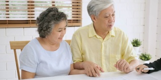 亚洲资深夫妇在家里得到理财规划师的建议。老在家里。