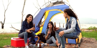 三个女人花周末时间露营和一起在日落的水边喝酒