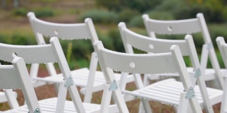 在婚礼现场，各种各样的白色折叠椅被雨水打湿