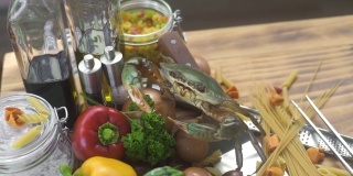 意大利餐厅的活螃蟹和新鲜蔬菜。在意大利海鲜餐厅的生蔬菜和干意面上的活螃蟹。海鲜美食的概念。健康饮食与节食