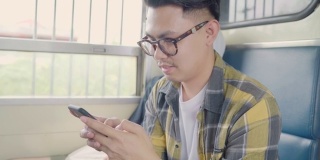 一名亚洲男子在坐火车时用智能手机查看社交媒体。