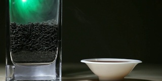 黑热的中国茶杯，绿色的烟，木桌，黑色的背景，没有人高清的画面