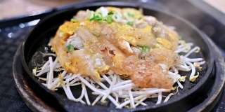 特写慢镜头的泰国食物或街头食物在热盘在餐厅服务。用面粉和豆芽炒生蠔，盛于热板内。